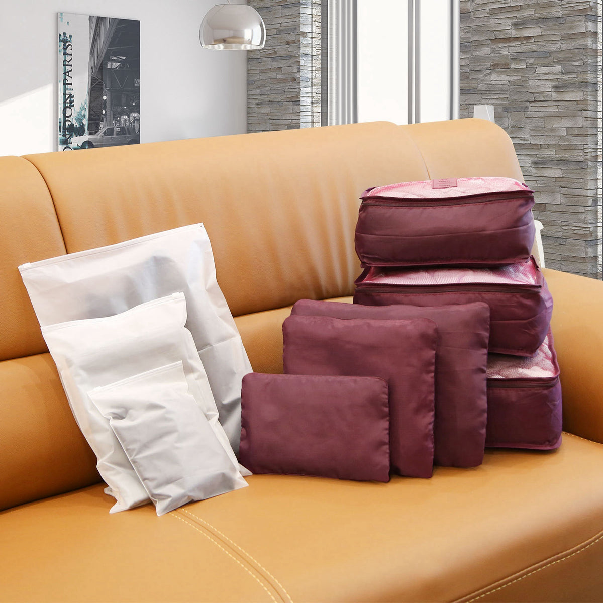Burgundy packing cubes and pouches with three translucent storage bags on a sofa