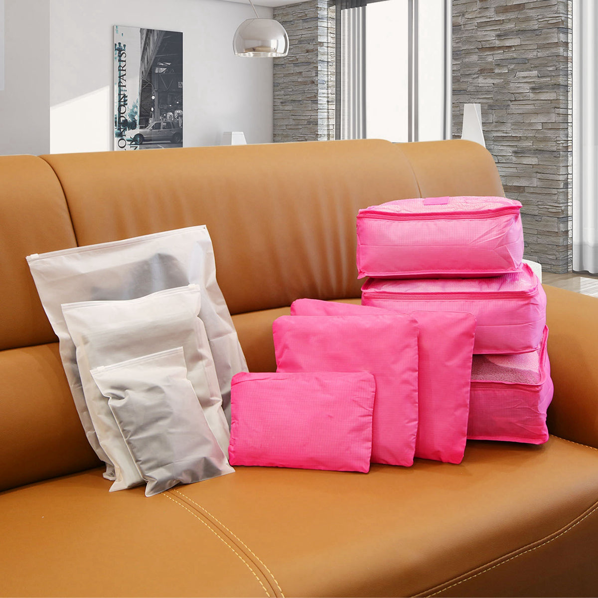 Hot pink packing cubes and pouches with three translucent storage bags on a sofa